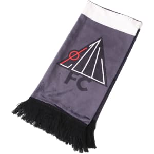 A velvet scarf in shades of grey and white, featuring a logo and black fringes at the ends.
