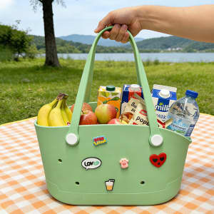 A light green EVA pet bag filled with fruits, drinks, and decorated with playful stickers. It has a logo on one side.