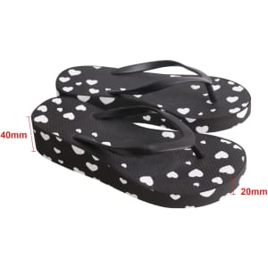 A pair of black thongs with white heart patterns, featuring a raised platform design.