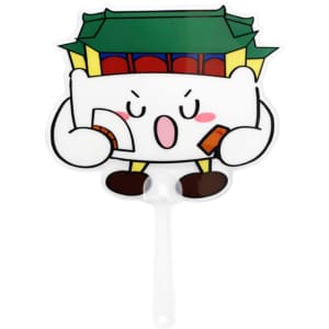 A transparent PVC hand fan featuring a playful character holding items, with a green and red building design.