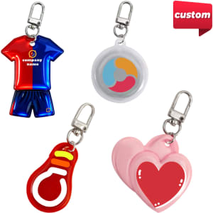 Four custom shape reflective keychains in various colours: a jersey, a circle, a lightbulb, and pink hearts, each with a clip.
