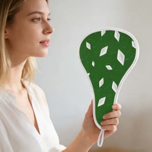 A woman holding a foldable fan with a green leaf design and a white border, featuring a logo on the handle.