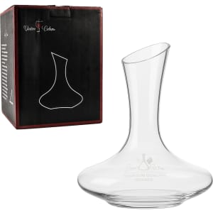 A glass wine decanter with a sleek design, displayed beside its packaging featuring a logo.
