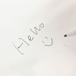 A5 whiteboard notebook featuring a handwritten note and smiley face, with a black marker on a white background.