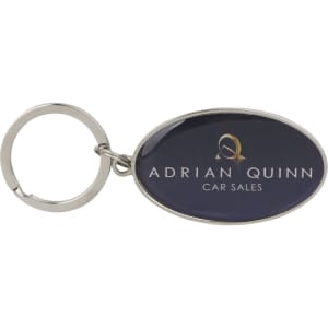 A metallic keyring with a silver ring and an oval epoxy domed surface featuring a logo.