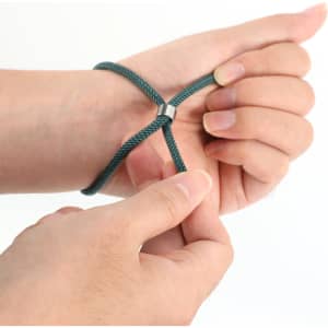 A green metal woven bracelet is being adjusted on a person's wrist, showcasing its flexible design.