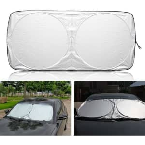 A foldable car shade in silver, featuring a circular design, displayed on a car windshield. It has a logo.