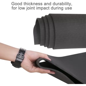 A premium TPE yoga mat in black, showcasing its thickness and durability, with a hand holding one edge.
