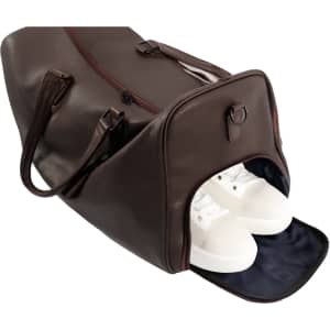 A brown polyurethane duffle bag with a zippered opening, revealing white shoes inside. It has handles and a logo.