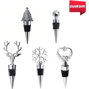 A collection of five stainless steel bottle stoppers in various festive designs, including a Christmas tree and a snowflake.