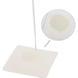 An absorbent paper coaster in a white square shape, showcasing liquid being absorbed in the centre.