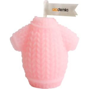 A pink sweater-shaped candle with a textured knit design and a small flag. It includes a branding logo.