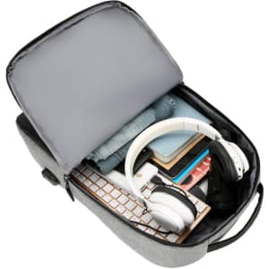 A grey laptop backpack with a USB charging port, packed with headphones, clothing, and various accessories.