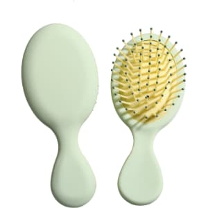A mini paddle brush in pastel green, featuring a smooth oval design and rounded pins for gentle grooming.