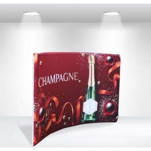 A tabletop tension fabric display featuring a champagne bottle on a red background with decorative ribbons and ornaments.