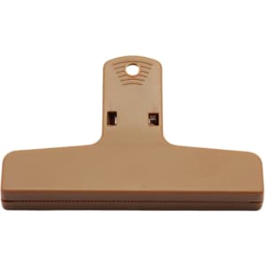 A tan plastic magnetic clip with a large flat surface and a hanging hole for easy storage.