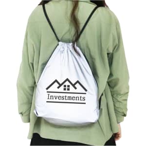 A reflective drawstring bag in white, being carried on a person's back. The bag features a logo.