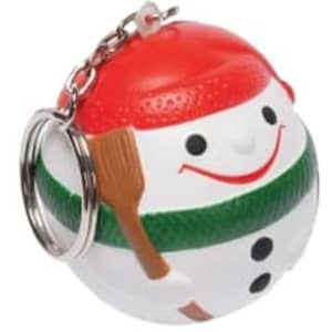 A snowman-shaped stress ball keyring in white, red, and green with a smiling face and a wooden shovel.