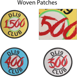 Four custom woven patches in various colours, featuring circular designs with different numerical values and a logo.