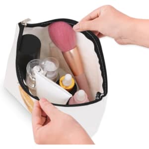 A canvas cosmetic bag in white, filled with various beauty products, including bottles and a makeup brush.