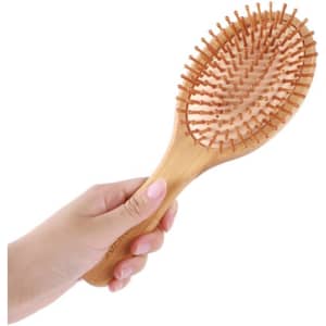 A bamboo airbag hair brush featuring a wooden handle and soft bristles, held in a hand.