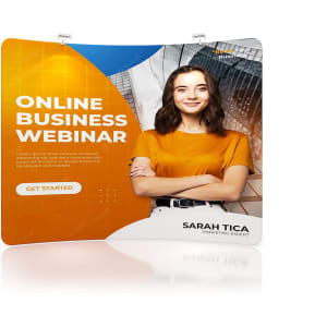 A C-shaped tension fabric display wall in orange and blue featuring a smiling woman and promotional text.