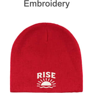 A red beanie with an embroidered design featuring a sun and the word "RISE." It has branding as well.