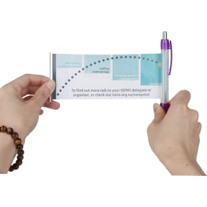 A purple plastic pen featuring a banner design, held between two hands, with various graphics and text visible.