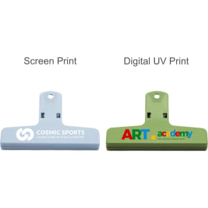Two plastic magnetic clips in blue and green, featuring different designs and print styles. Each has a logo.