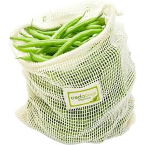 A white organic cotton mesh bag filled with fresh green beans, featuring a logo on the side.