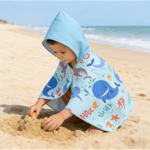 A kids' hooded towel in light blue featuring playful ocean-themed prints, perfect for beach or bath use.
