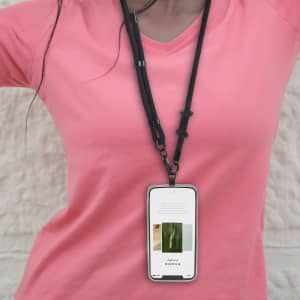 An adjustable black phone lanyard worn around the neck, holding a smartphone in front of a person wearing a pink shirt.