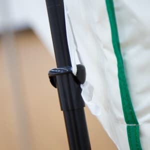 A close-up of a specially designed attachment on a black pole, featuring a green and white tent fabric.