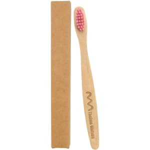 A small bamboo toothbrush with a pink bristle head, positioned next to its brown cardboard packaging.