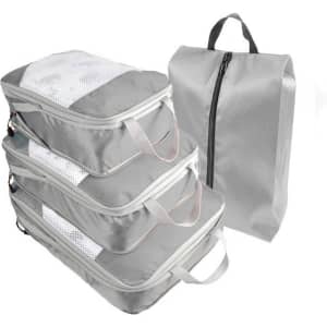 A set of grey travel packing cubes in various sizes, with a matching grey storage bag, featuring mesh panels and handles.