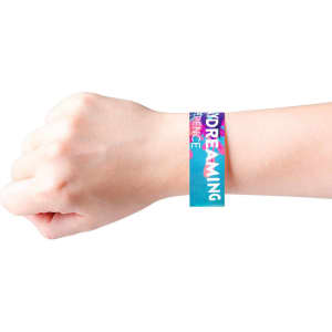 A colourful disposable Tyvek wristband featuring a vibrant design, worn on a hand. The wristband has a logo.