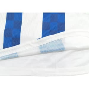 A breathable white T-shirt featuring blue checkered stripes, with a set-in shoulder design, and a logo present.