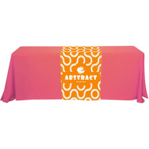 A large table runner in vibrant pink with an abstract orange and white design, featuring a logo at the centre.