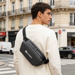 A black fanny pack with a logo, worn across the body by a person in an urban setting.