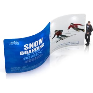 A curved, colourful S-shaped fabric display wall featuring images of skiers, with a person standing next to it for scale.