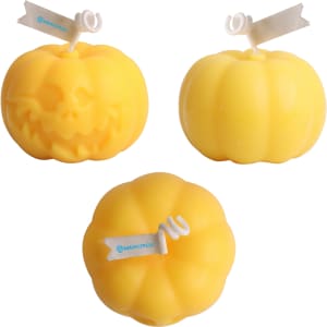 Three pumpkin-shaped candles in vibrant yellow, featuring varying designs, including one with a skull motif.