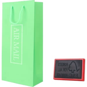 A green paper bag with handles alongside a red stamp, featuring a logo and text.