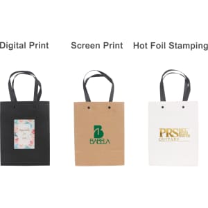 Three vertical paper bags feature knitted handles: a black bag, a brown bag with green text, and a white bag with gold text.