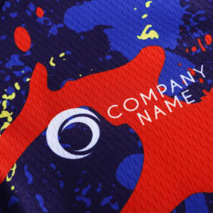 A close-up of a men's cycling jersey featuring a vibrant design with red, blue, and yellow splashes, and a logo.