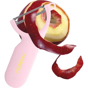 A pink vegetable peeler with a metal blade, alongside a partially peeled red apple and a long strip of apple skin.
