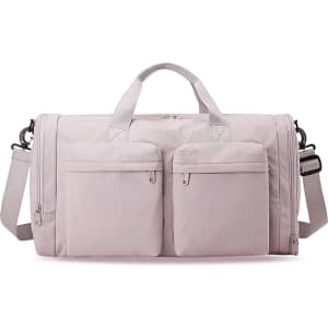 A foldable travel duffle bag in light pink with two front pockets and a shoulder strap. It also has a logo.