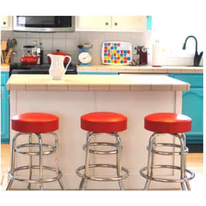 Three custom barstools with red seats and chrome bases arranged neatly at a kitchen island with a bright blue and white background.