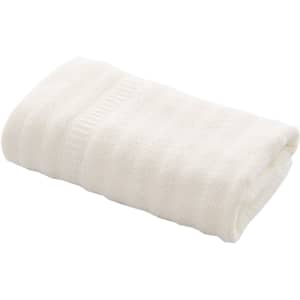 A cream-coloured bamboo fiber towel neatly folded, featuring a textured pattern. It includes a branded tag.