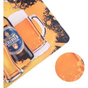 A rubber counter mat features a vibrant design with images of beer bottles and glasses in shades of yellow and orange.