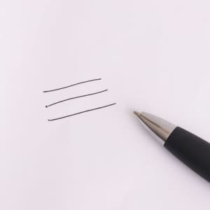 A black stylus pen rests beside three straight lines drawn on white paper. The pen has a sleek design and shiny tip.
